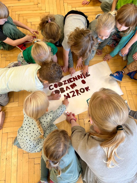 Dzieci dotykają literki wycięte z różnych papierów ściernych.